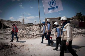 Em meio à destruição da guerra, a bandeira do ACNUR é levada adiante durante um cessar-fogo em Aleppo, que permitiu a entrega de ajuda humanitária desesperadamente necessária. Foto: © UNHCR / B.Diab 