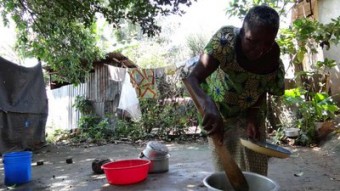 Mama Furaha mexe a comida no jardim de sua amiga, Cady, que acolheu ela e seus netos em sua casa.