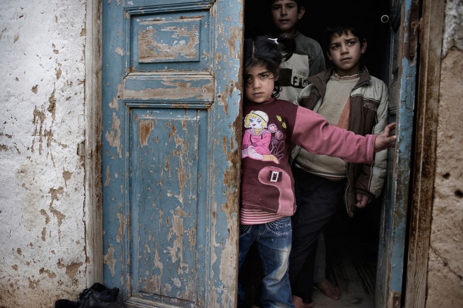 Crianças sírias se abrigam na entrada de uma casa em área afetada pelo conflito. Foto: UNICEF/Alessio Romenzi